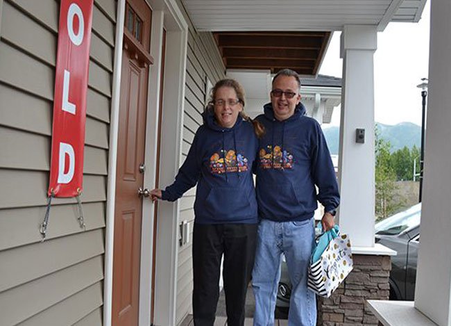 A couple posing in front at the porch of a house